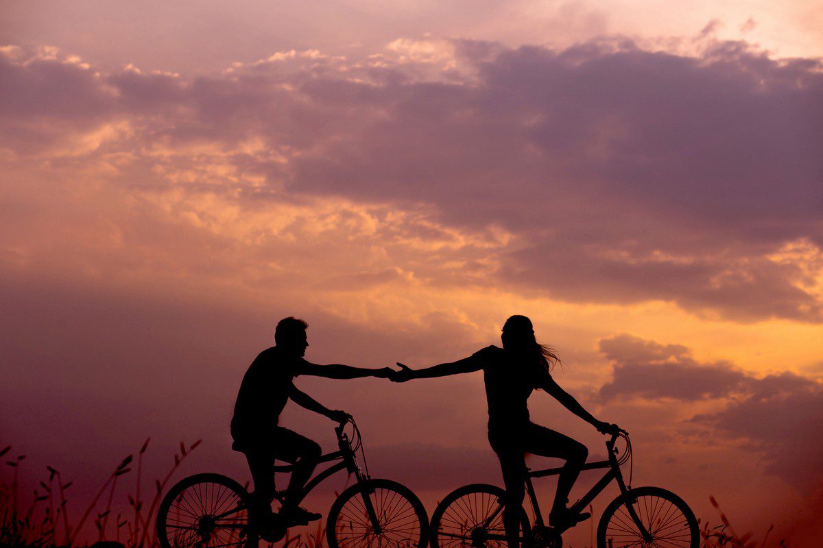 young couple on bicycles against sunset