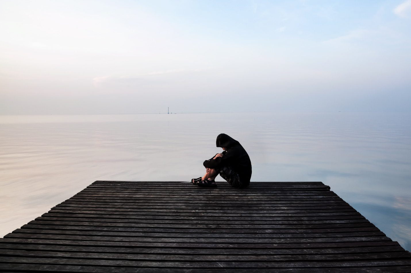 Frustrated depression man sitting on wooden bridge, near the beach