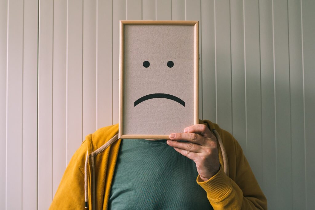 man holding picture frame with sadness and depressive emoticon