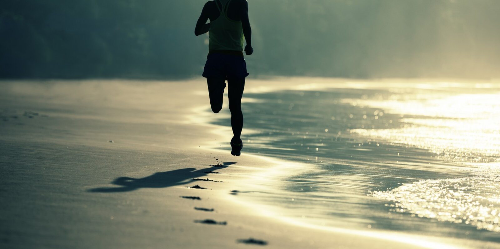 fitness woman runner running on sunrise beach