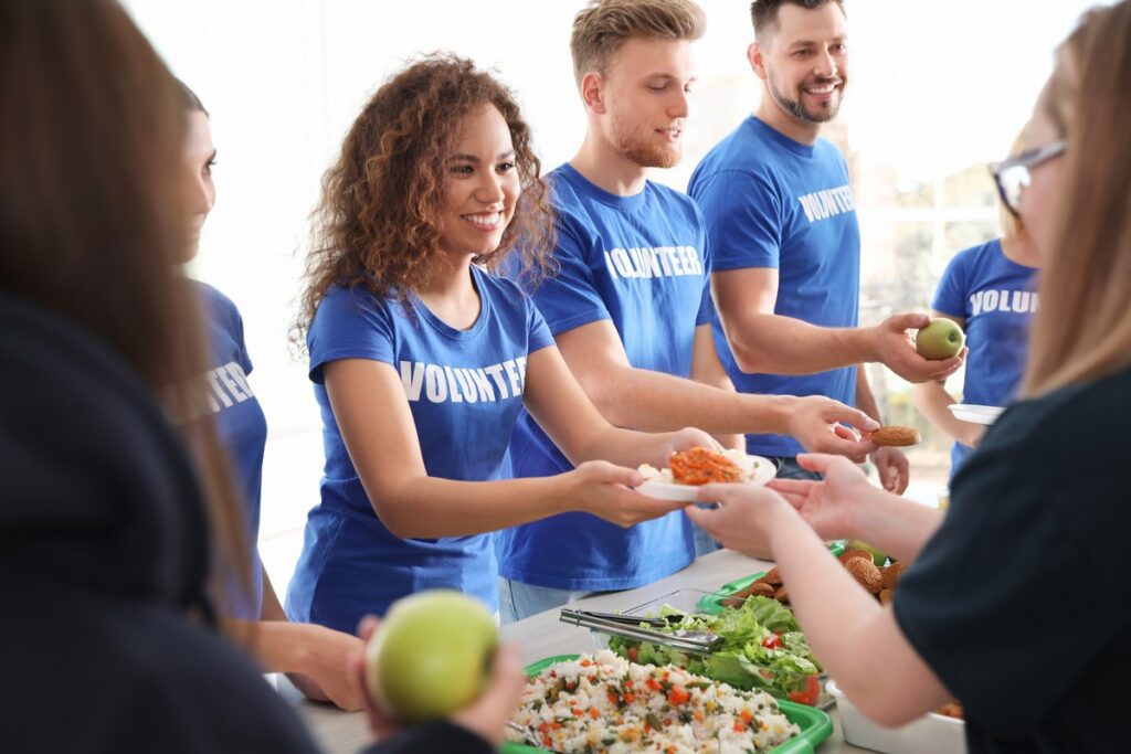 Volunteers serving food to poor people indoors